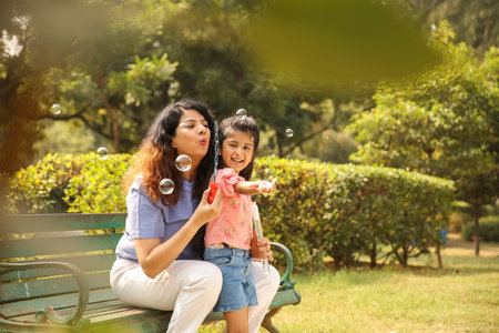 Mother and daughter blowing soap bubbles in the park. Happy family conceptの写真素材