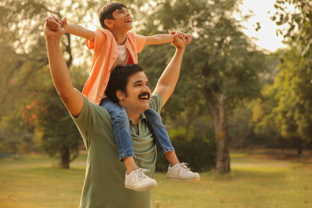 Father giving piggyback ride to son in park on sunny dayの写真素材
