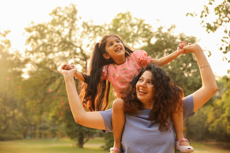 Mother and daughter having fun in the park at sunset. Family happiness concept.の写真素材