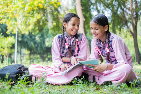 Two girls reading book together in the park. Education and learning concept.の写真素材
