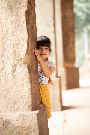 Cute little girl standing in front of a stone wall in the templeの写真素材