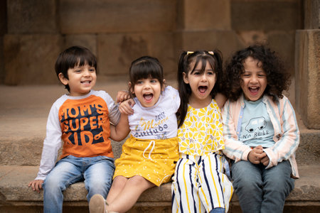 Group of happy kids sitting on the stairs in a park.の写真素材