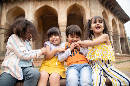 Group of happy children sitting on the bench in Agra, Indiaの写真素材