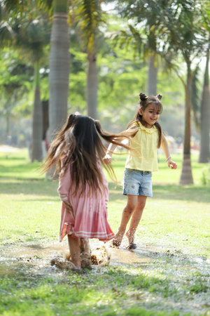 Two little girls playing in a puddle in the park on summerの写真素材