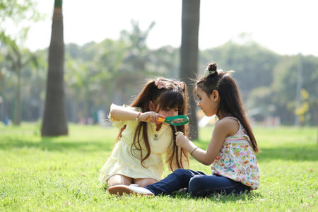 Little girls playing with magnifying glass in the park, education conceptの写真素材