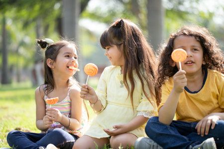 Group of happy children eating lollipops in the park.の写真素材