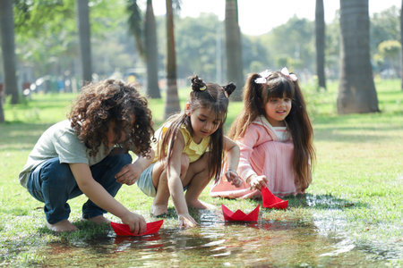 Children playing with paper boats in the park on a hot summer dayの写真素材
