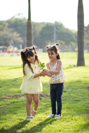 Two little asian girls holding a bunch of flowers in the parkの写真素材