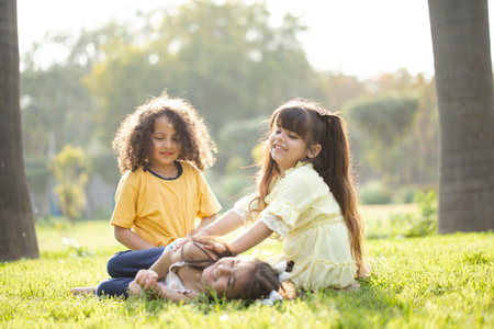 Portrait of two little girls sitting in the park and looking at cameraの写真素材