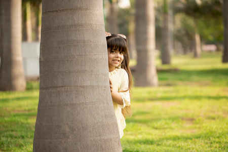Happy little girl smiling and playing in the park with tree.の写真素材