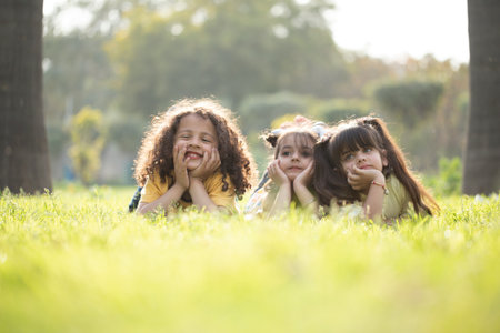 Three little girls lying on the grass in the park and laughing.の写真素材