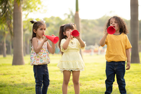 Group of children playing with red megaphone in the park.の写真素材