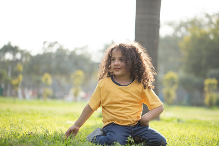 Portrait of a little boy sitting on the grass in the parkの写真素材