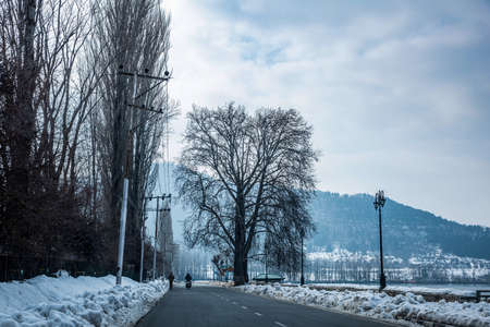 Road next to Dal Lake in winter, and the beautiful mountain range in the background in the city of Srinagar, Kashmir, India.の写真素材