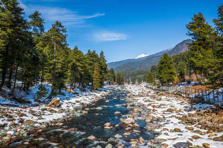Beautiful view of Pahalgam during winter season surrounded by snow frozen Himalayas glacier mountains and green fir and pine tree line forest landscapeの写真素材