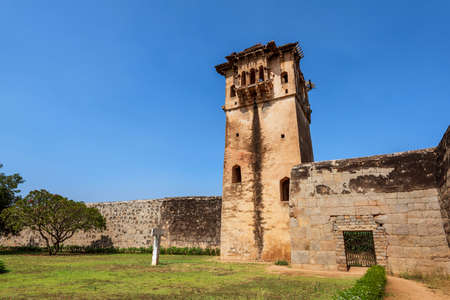Hampi, Karnataka, India - January 14, 2020 : Zanana Enclosure. Base of demolished and disappeared Queens Palace with watch tower in back under blue cloudscape. Green foliage and grass. Hampi, Karnataka, Indiaのeditorial素材
