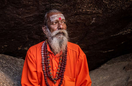Hampi, Karnataka, India - January 11, 2020 : A monk dressed in orange, sitting among the stones of Kampa Bhupa's Path in Hampi.のeditorial素材