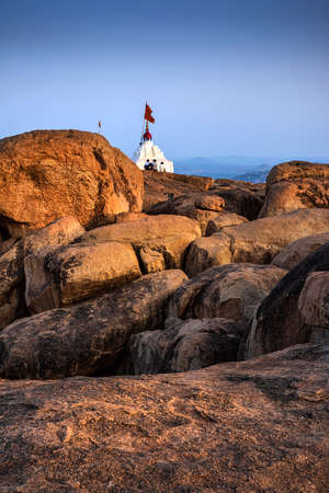 Hampi, Karnataka, India - January 15, 2020 : View of Kishkinda, Anjanadri Hill, (Monkey Temple) Anjaneya Parvat, the birthplace of Hanuman God now a white temple on top of beige boulder hill, Hampi.のeditorial素材