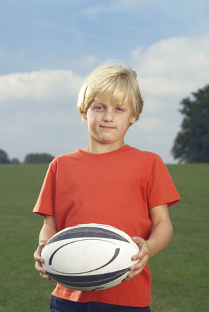 Boy holding rugby ball in filedの写真素材