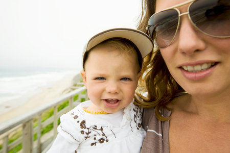 Woman carrying baby girl on beachの写真素材