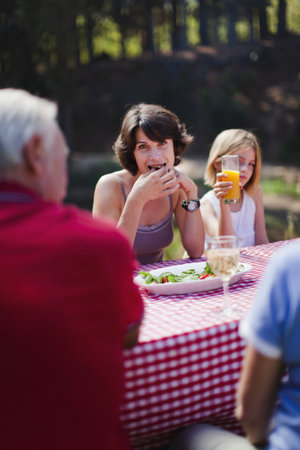 Woman eating with family at picnic tableの写真素材