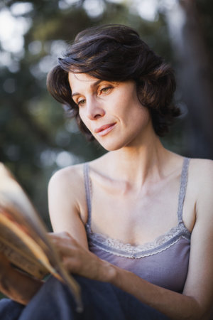 Woman reading book outdoorsの写真素材
