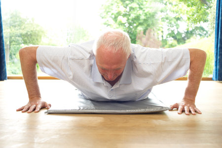 Older man doing pushups indoorsの写真素材