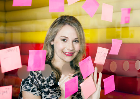 Businesswoman sticking notes on windowの写真素材