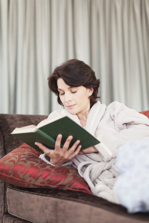 Woman in bathrobe reading bookの写真素材