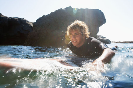 Man lying on surfboard in the water.