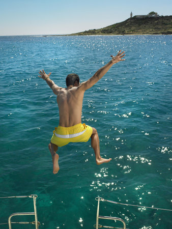 Man jumping into sea from boat, rear viewの写真素材