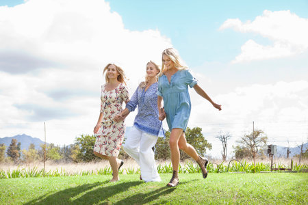 Mother and daughters running in gardenの写真素材