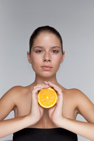 Woman holding halved orangeの写真素材