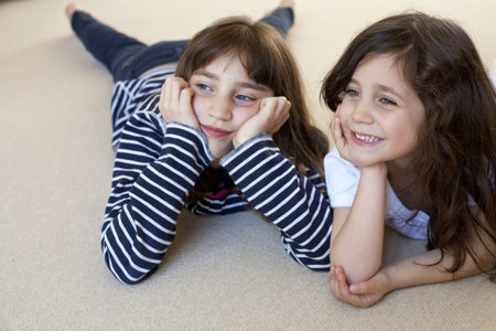 Girls watching television on carpetの写真素材