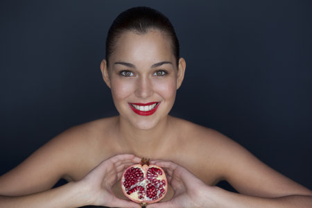 Woman holding halved pomegranateの写真素材