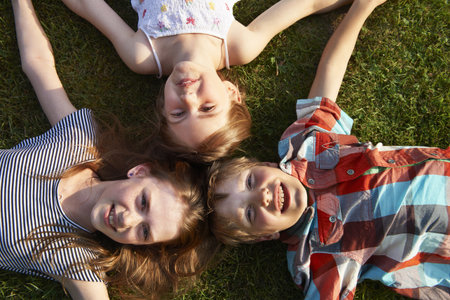 Children laying in grass togetherの写真素材