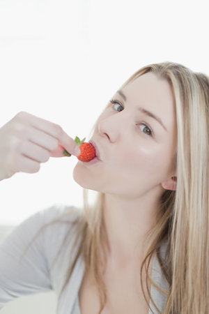 Smiling woman eating strawberryの写真素材