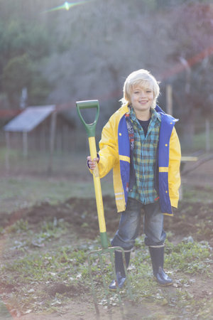 Boy holding pitchfork in gardenの写真素材