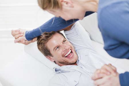Couple playing together on couchの写真素材