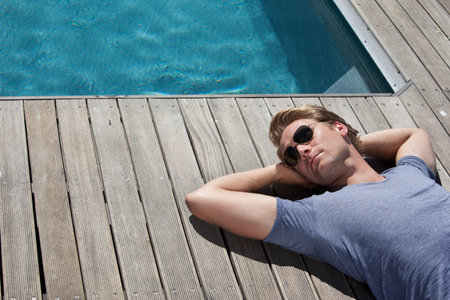 Man relaxing by swimming poolの写真素材