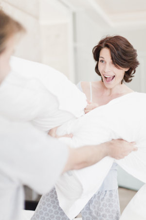 Smiling couple having pillow fightの写真素材