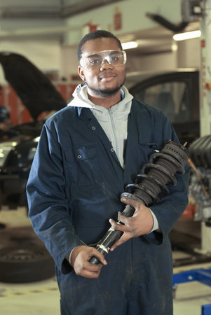 Student carrying car part in garageの写真素材