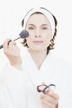 Woman in bathrobe applying makeupの写真素材