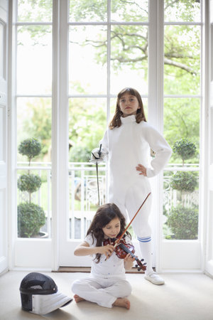 Two girls with violin and fencing gearの写真素材
