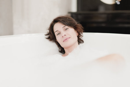 Smiling woman taking bubble bathの写真素材