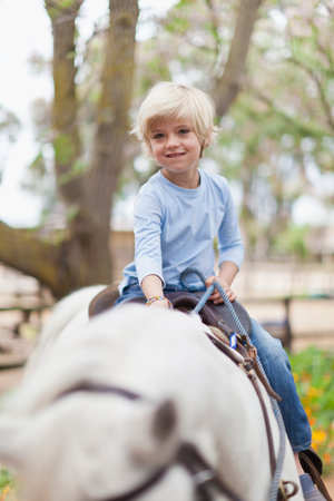 Smiling boy riding horseの写真素材