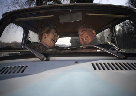 Senior couple sitting in car, smiling at each other
