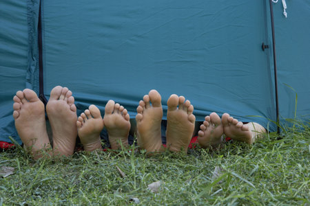 Four people's feet sticking out of tent door.の写真素材