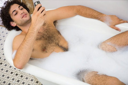 Man using a cellular telephone in the bathの写真素材
