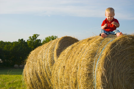 Baby boy sitting on a haystackの写真素材